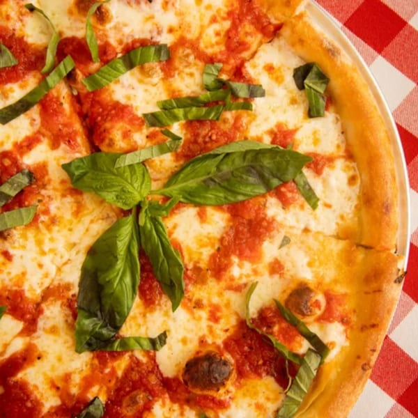 Close-up of a Rocky's Pizza Bar Margherita pizza with fresh basil on a red and white checkered tablecloth.