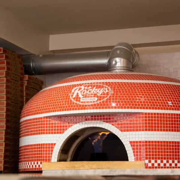 Rocky's Pizza Bar's red and white tiled pizza oven with a visible flame inside.