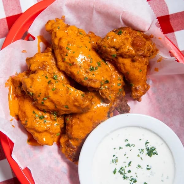 Rocky's Pizza Bar buffalo wings in a red basket with a side of ranch dressing.